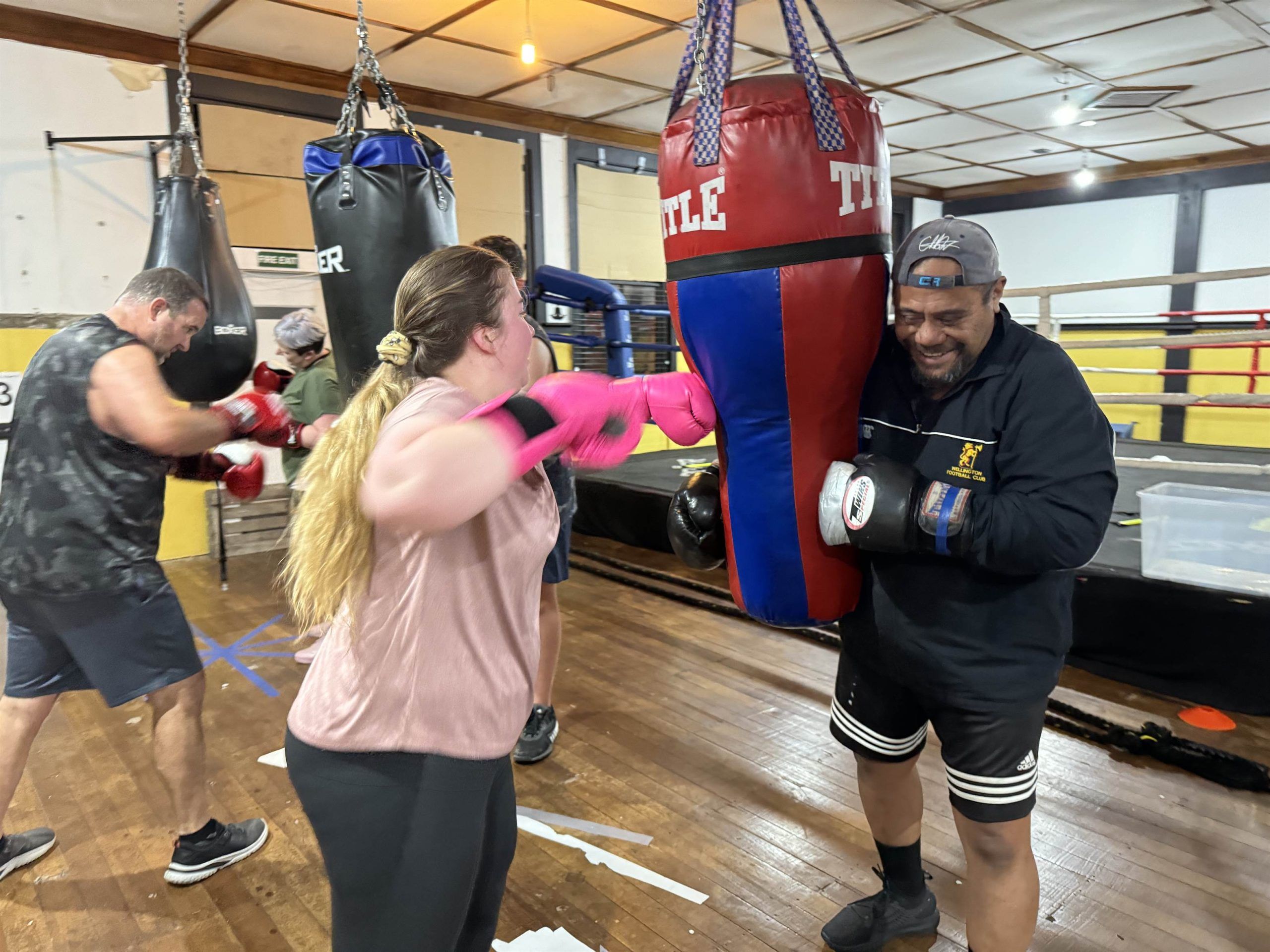 An adult in pink gloves working the pads with a coach.